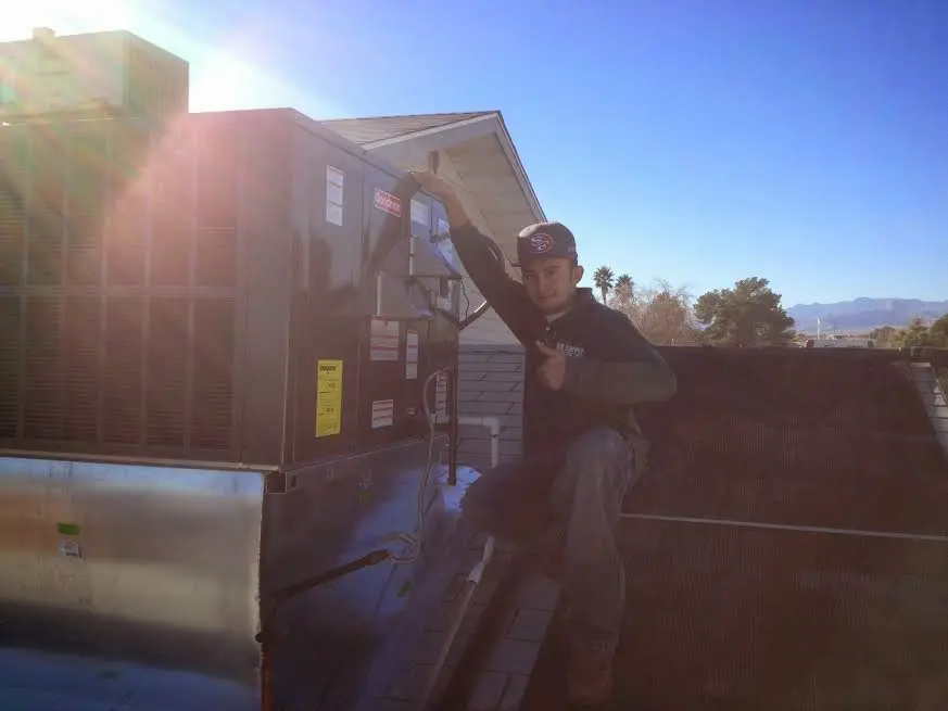 HVAC technician performing Air Duct Cleaning on a rooftop unit in Bernalillo